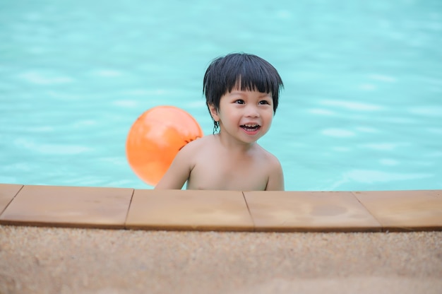 bambino che impara a nuotare e godersi l'estate in piscina presso il parco acquatico