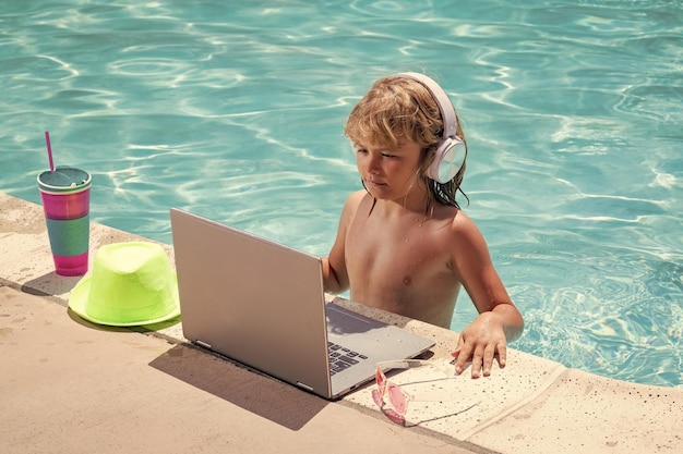 Bambino che lavora con il portatile durante le vacanze estive piccolo freelance che usa il telecomando del computer