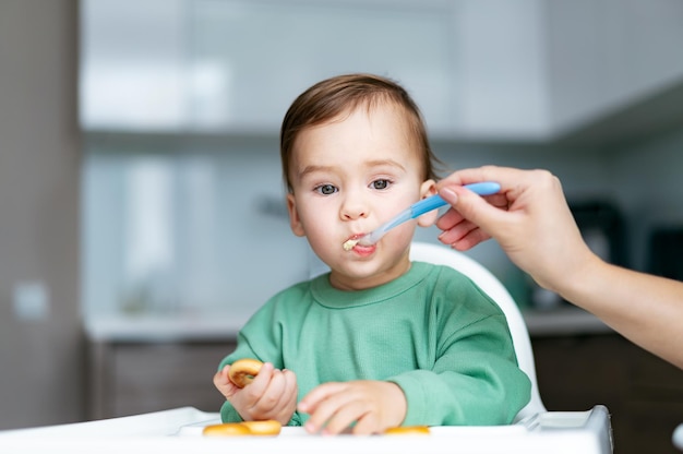 Bambino che mangia cibo in cucina Purea di figlio di alimentazione madre