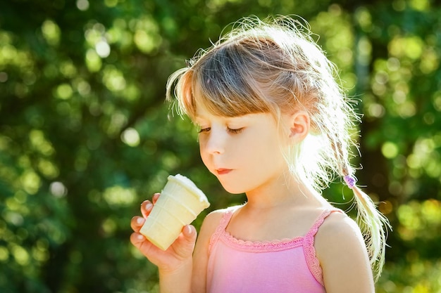 Bambino che mangia il gelato nel parco sullo sfondo