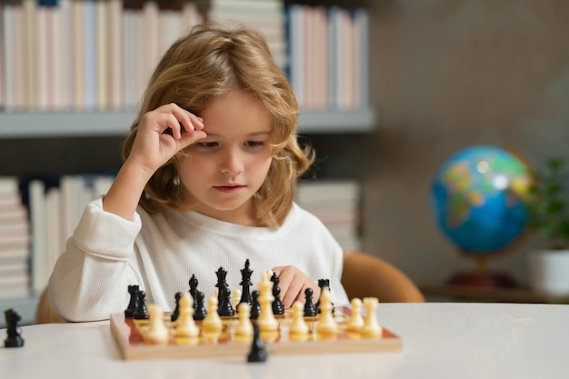 Bambino che pensa agli scacchi Bambino che gioca a scacchi Bambino che gioca a un gioco da tavolo Bambino che pensa al brainstorming e all'idea nel gioco degli scacchi Scuola di scacchi e istruzione Gioco di logica per bambini e pensiero logico