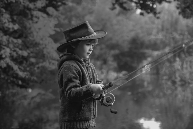 Bambino che pesca al lago d'autunno Capretto con la canna da pesca