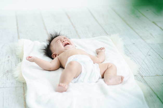 Bambino che piange in un pannolino sul pavimento