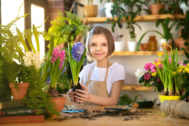 Bambino che pianta fiori primaverili. Il giardiniere della bambina pianta il giacinto. Ragazza con giacinto in vaso di fiori. Bambino che si prende cura delle piante. Strumenti da giardinaggio. Copia spazio.