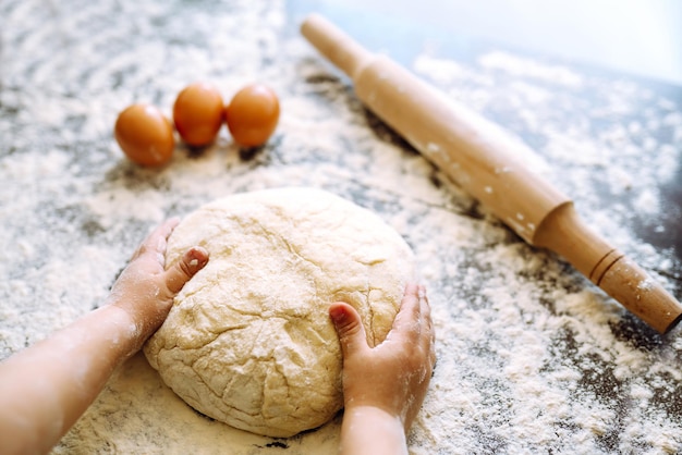 Bambino che prepara la pasta per la cottura. Piccole mani che impastano pasta e pasta arrotolata