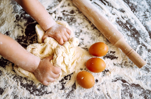 Bambino che prepara la pasta per la cottura. Piccole mani che impastano pasta e pasta arrotolata