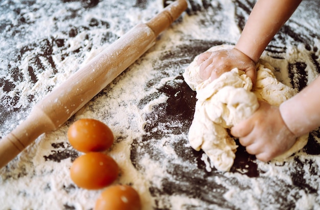 Bambino che prepara la pasta per la cottura. Piccole mani che impastano pasta e pasta arrotolata