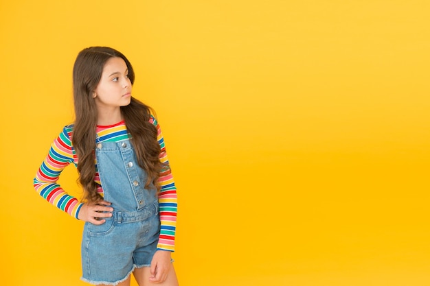 Bambino che presenta lo spazio della copia del prodotto Buon giorno dei bambini infanzia punte hipster ragazza vestiti colorati ottimista concetto piccola ragazza sfondo giallo estate bambino moda pubblicità concetto