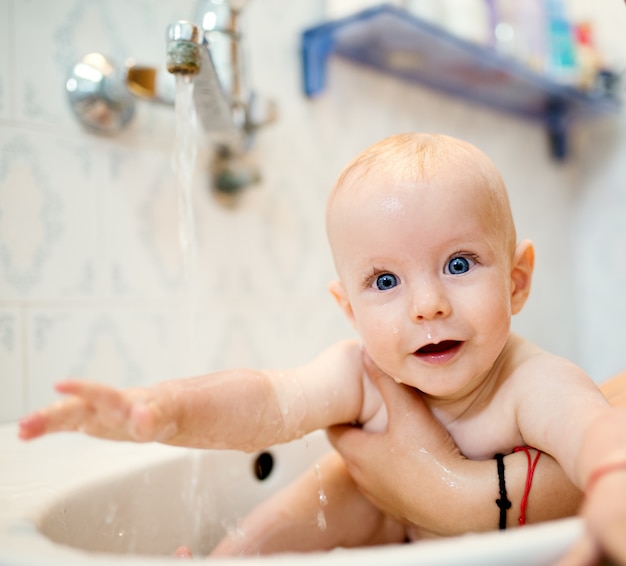 Bambino che ride felice facendo un bagno. Piccolo bambino in una vasca da bagno. Bambino sorridente in bagno. Lavaggio e balneazione infantili. Igiene e cura dei bambini piccoli.