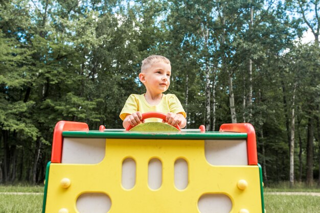 Bambino che ride sveglio che gioca su una diapositiva in un parco giochi fuori sotto il sole estivo.