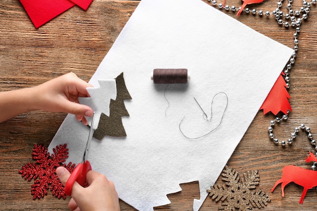 Bambino che ritaglia l'albero di Natale dal feltro a tavola