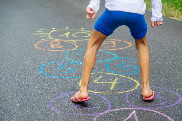 Bambino che salta classici sul marciapiede. Messa a fuoco selettiva.