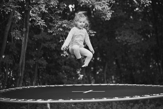 Bambino che salta su un trampolino nel giardino serale in Danimarca