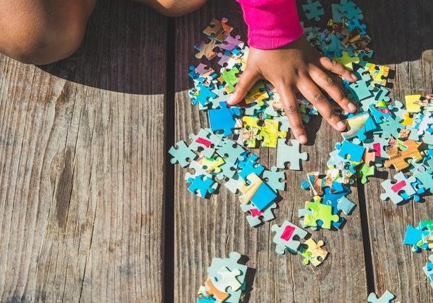 Bambino che seleziona i pezzi del puzzle su un ponte di legno