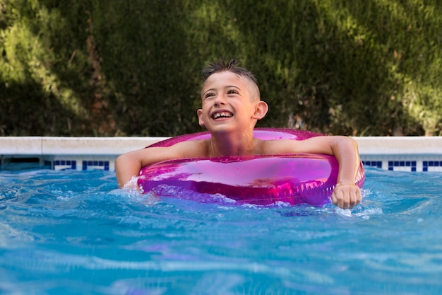 Bambino che si diverte con galleggiante a bordo piscina