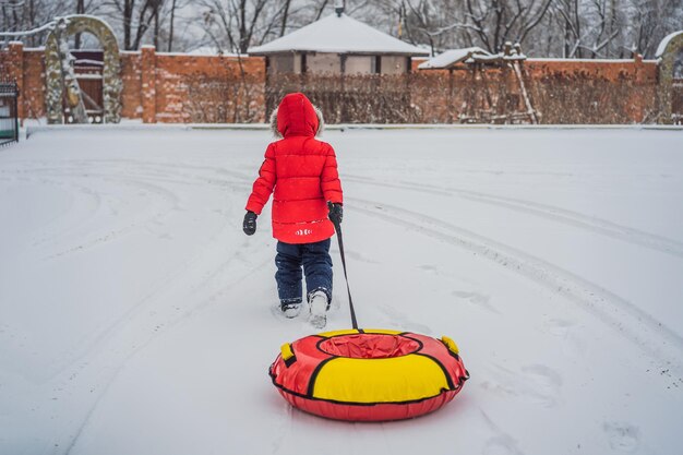 Bambino che si diverte sul tubo di neve Il ragazzo sta cavalcando un tubo Divertimento invernale per i bambini