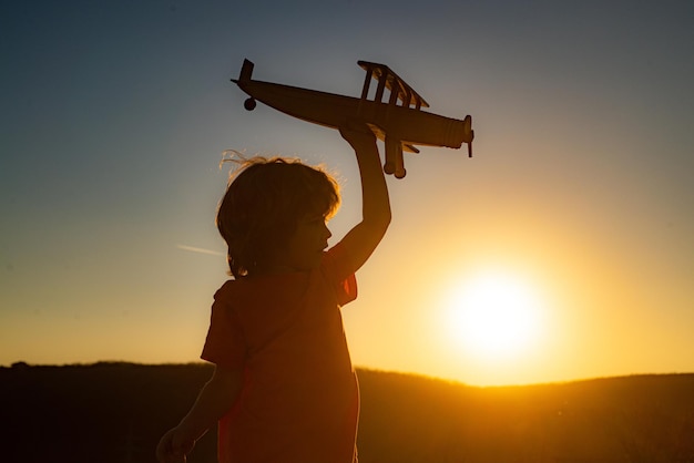 Bambino che sogna. Aviatore pilota del ragazzo con l'aeroplano. Sogni di viaggiare. I bambini sognano. Bambino sullo sfondo del cielo al tramonto.