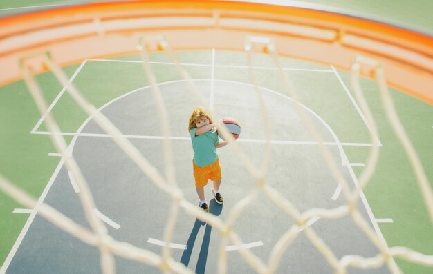 Bambino che spara palla da basket e gioca a basket vista inferiore grandangolare