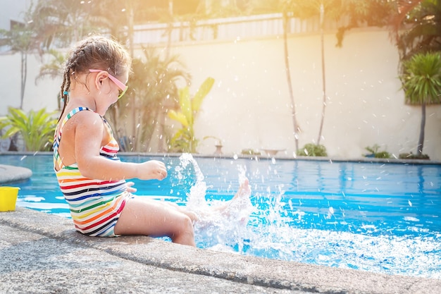 Bambino che spruzza acqua nella piscina in vacanza