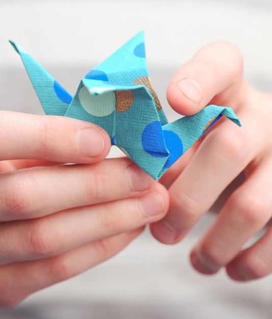 Bambino che tiene la gru di origami da vicino