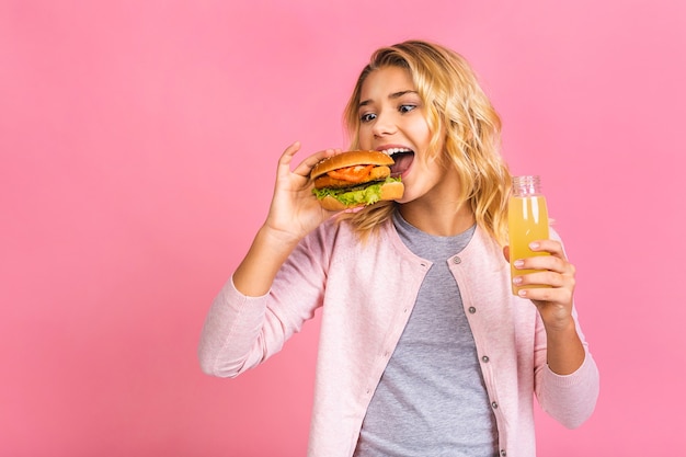 Bambino che tiene un pezzo di hamburger e limonata.