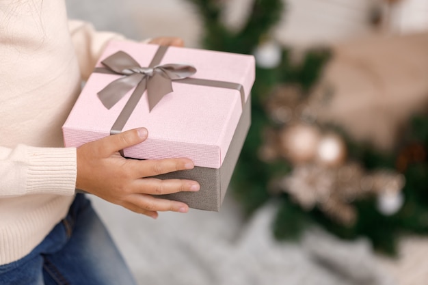 Bambino che tiene una bella confezione regalo vicino all'albero di Natale