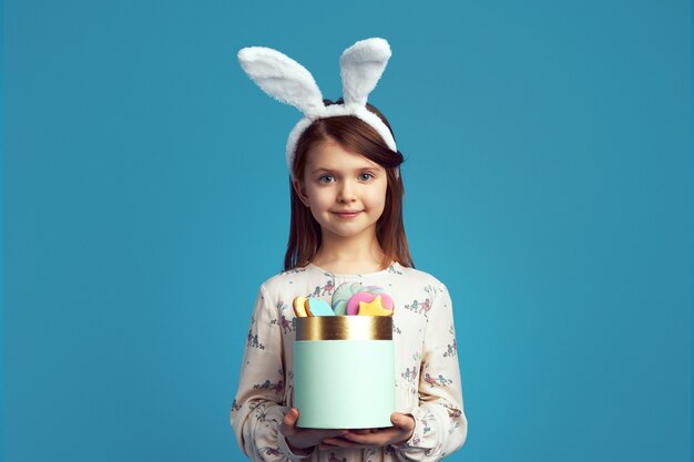 Bambino che tiene una scatola con biscotti con orecchie da coniglio e vestito carino