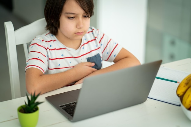 Bambino che utilizza il computer portatile a casa al chiuso