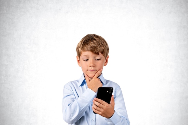 Bambino che utilizza il telefono con la mano sul mento spazio copia sfondo grigio