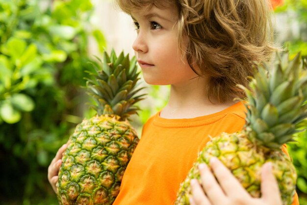 Bambino con ananas in giardino bambini in vacanza estiva in famiglia resort tropicale sulla frutta esotica dell'isola