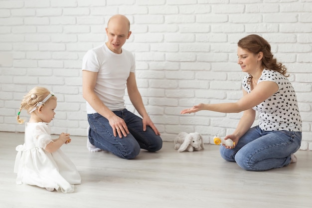 Bambino con apparecchi acustici e impianti cocleari gioca con i genitori sul pavimento Concetto di sordo e riabilitazione