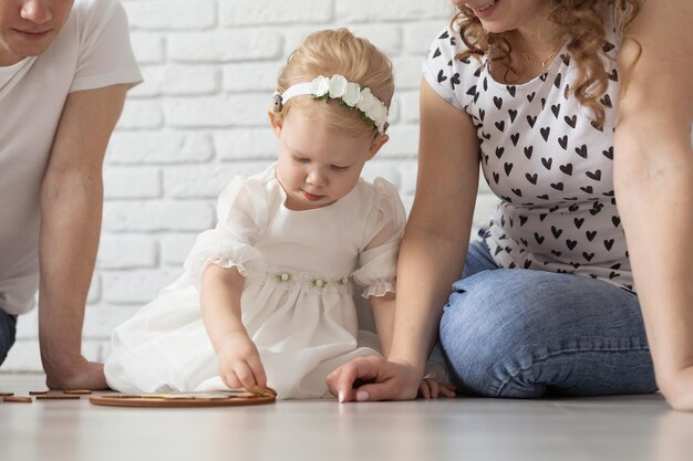 Bambino con apparecchi acustici e impianti cocleari gioca con i genitori sul pavimento Concetto di sordo e riabilitazione