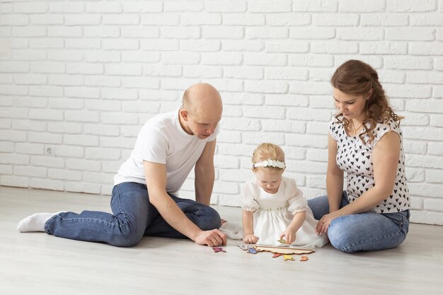 Bambino con apparecchi acustici e impianti cocleari gioca con i genitori sul pavimento Sordi e concetto di riabilitazione e diversità