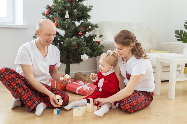 Bambino con apparecchio acustico e impianto cocleare che si diverte con i genitori nella stanza di natale Diversità sorda, salute e diversità