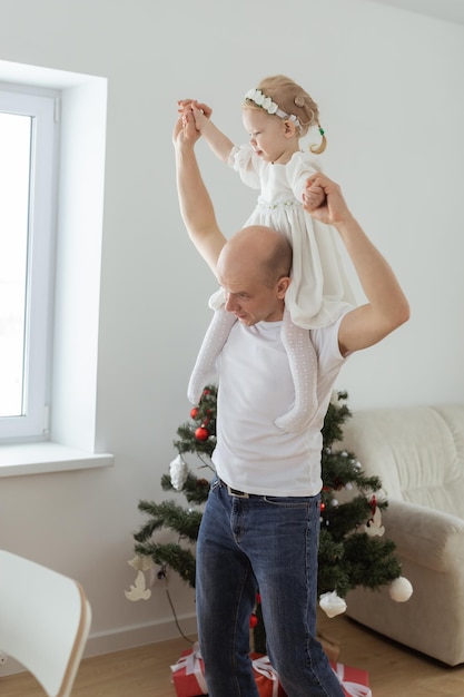 Bambino con apparecchio acustico e impianto cocleare che si diverte con il padre sullo sfondo dell'albero di Natale Diversità sorda e concetto di salute