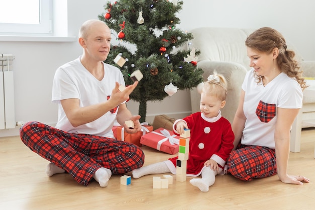 Bambino con apparecchio acustico e impianto cocleare divertendosi con i genitori nella stanza di natale sordo div