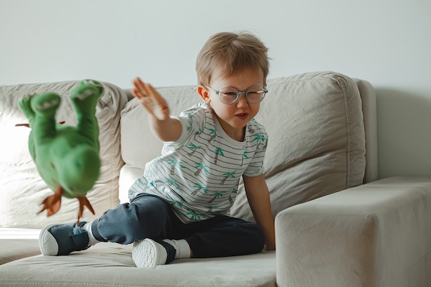 Bambino con autismo con gli occhiali si siede sul divano e triste