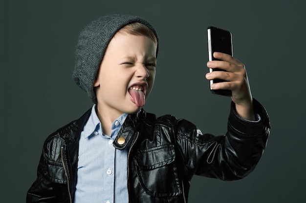 Bambino con cappello e giacca di pelle che si fa un selfie