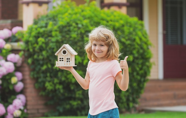 Bambino con casette giocattolo in mani mutuo all'aperto assicurazione casa futura piani di protezione dei bambini