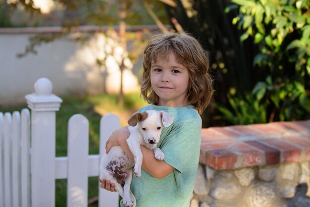 Bambino con cuccioli che si baciano e abbracciano un bambino adorabile con il cane che cammina all'aperto