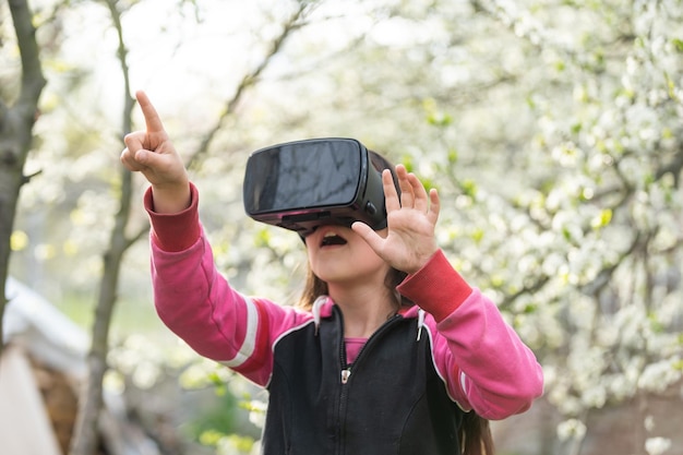 Bambino con cuffia per realtà virtuale seduto dietro natrue all'aperto a casa.