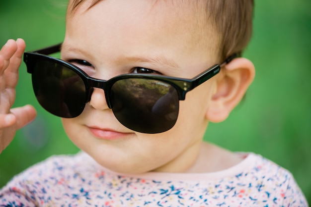 Bambino con gli occhiali da sole sull&#39;erba verde