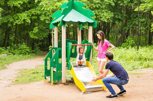 Bambino con i genitori al parco giochi. Mamma, papà e figlia. suonare la famiglia.