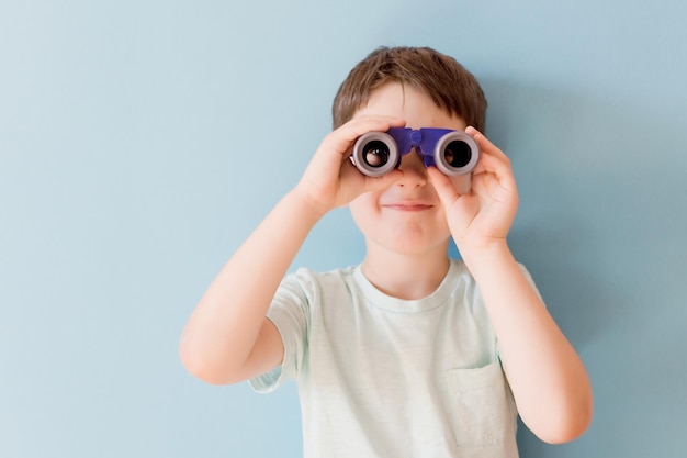 Bambino con il binocolo su sfondo blu