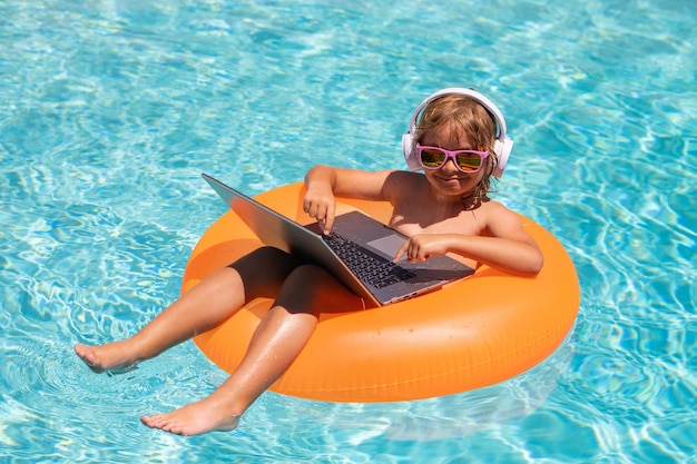 Bambino con il computer portatile nell'acqua della piscina nel giorno d'estate laptop impermeabile attività estiva all'aperto