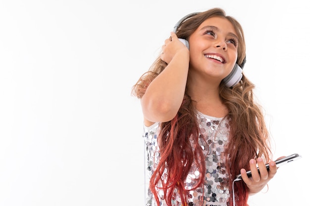 Bambino con il telefono in mano alza lo sguardo e ascolta la musica in cuffia