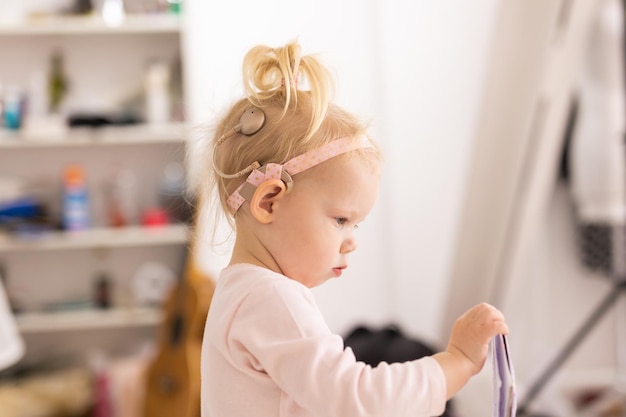 Bambino con impianti cocleari che si diverte a casa. Concetto di sordità e tecnologia medica.