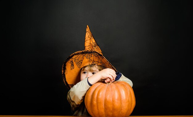 Bambino con jackolantern dolcetto o scherzetto ragazzino con cappello da strega con zucca di halloween