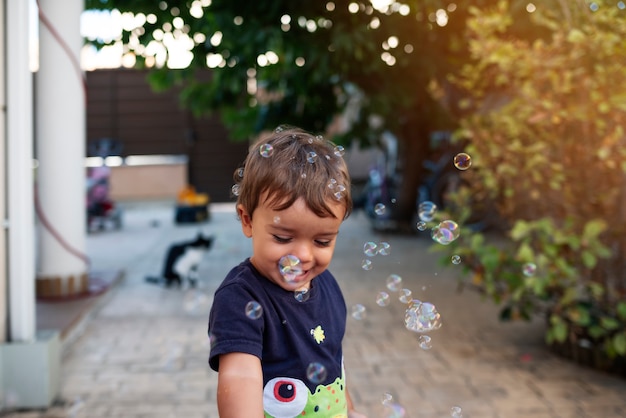 Bambino con la maglietta blu che gioca con le bolle di sapone