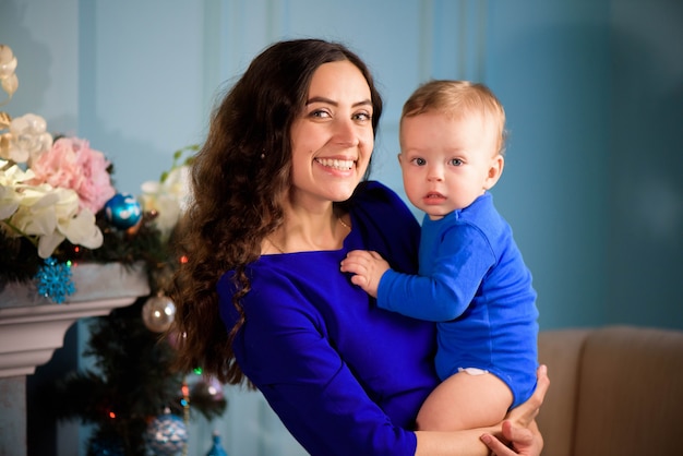 Bambino con la mamma nella stanza festosamente decorata con albero di Natale